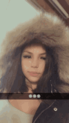a girl wearing a furry hooded jacket with three snowflakes on the bottom