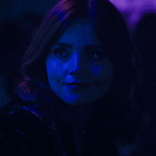 a close up of a woman 's face with a blue light behind her