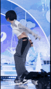 a person in a crop top and pants is dancing on a stage with the number 2 in the background