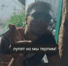 a man wearing sunglasses is holding a sign that says " lupat ho mbi teppm "