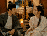 a man and a woman looking at each other with a lamp in the background