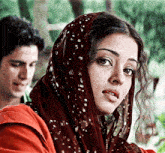 a woman wearing a red scarf with white dots on it looks at the camera