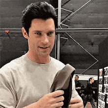 a man in a white shirt is holding a pair of shoes and smiling .