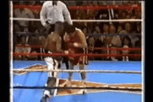 two boxers are fighting in a boxing ring with a referee in the background .