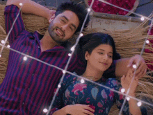 a man and a woman are laying next to each other holding hands and smiling