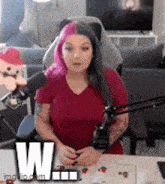 a woman in a red shirt is sitting in front of a microphone .