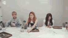 three women are sitting at a table with a sign that says twice