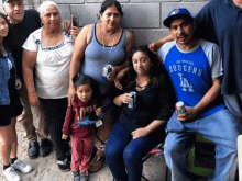 a man wearing a los angeles dodgers shirt sits with his family