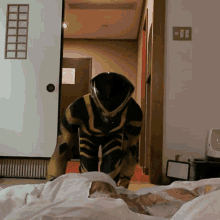 a man in a black and yellow superhero costume is kneeling on a bed