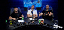 three men are sitting at a table in front of a frozen sign