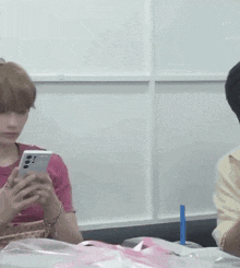a man in a pink shirt is holding a cell phone