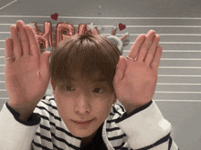 a young man making a face with his hands in front of a birthday balloon that says happy