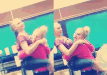 a girl in a pink shirt is holding another girl in a pink shirt