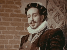 a man in a costume is standing in front of a brick wall and looking at something