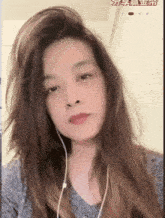 a woman wearing ear buds looks at the camera with chinese writing on the bottom right corner