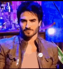 a man with a beard is wearing a jacket and a button on his jacket .