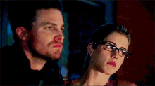 a man and a woman are looking at each other . the woman is wearing glasses .