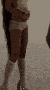 a woman in white underwear and white socks is standing in front of a white wall