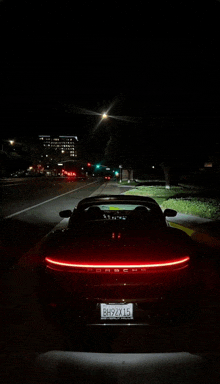 a porsche is parked on the side of a road at night