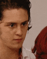 a close up of a man 's face with a red haired woman behind him
