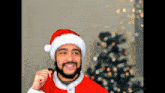a man wearing a santa hat is eating a chocolate bar in front of a christmas tree