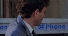 a man standing in front of a phone booth that says phone