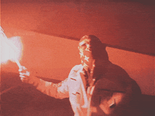 a person in a hooded jacket is holding a torch in a dark room