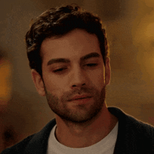 a man with a beard and a white shirt is looking down