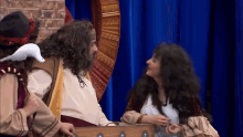 a man in a costume with a white bird on his head is talking to a woman in a costume