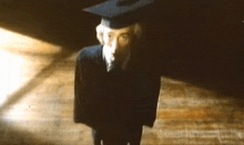 a man wearing a graduation cap and gown is standing on a wooden floor
