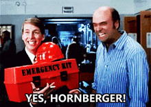 a man holding an emergency kit and another man holding a hard hat