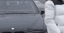 a man in a white jacket stands in front of a bmw car