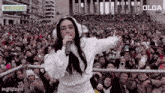 a woman wearing headphones singing into a microphone in front of a crowd .