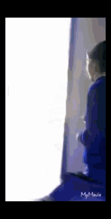 a man in a blue shirt is standing in front of a white wall with my movie written on the bottom right