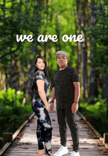 a man and a woman standing on a wooden bridge with the words we are one