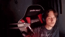 a man wearing headphones is sitting in a chair that says anda seat on it