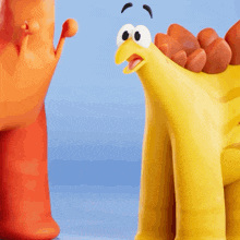 a yellow toy dinosaur is standing next to an orange toy