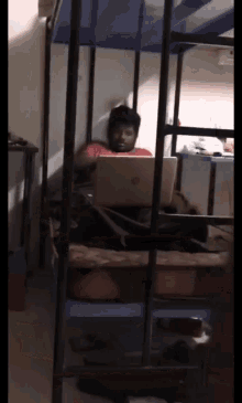 a man is laying on a bunk bed with a hp laptop