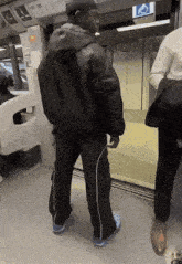 a man in a black jacket is standing in front of an elevator with a handicap sign above it