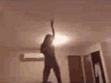 a woman is dancing in a room with a light on the ceiling .