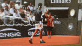 a tennis match is being played in front of an emirates advertisement on the wall