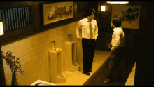 two men standing next to urinals in a bathroom with a picture on the wall that says ' flowers ' on it