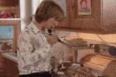 a woman in a kitchen with a picture of a house on the cabinet