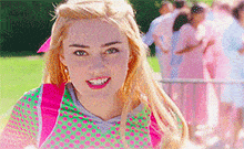a woman in a pink and green polka dot shirt is smiling .