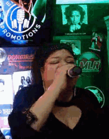 a woman is singing into a microphone in front of a sign that says promotions