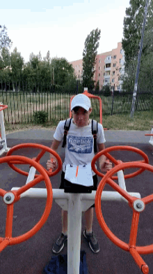 a boy wearing a reebok shirt is standing on a exercise machine