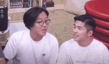 two men are sitting next to each other and one of them has a shirt that says " witness " on the front
