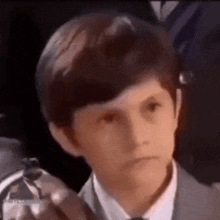 a young boy in a suit and tie is pointing at something .