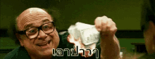 a man wearing glasses is holding a pile of money in his hand and smiling .