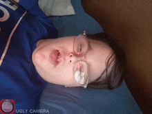a person wearing glasses laying on a bed with ugly camera written on the bottom